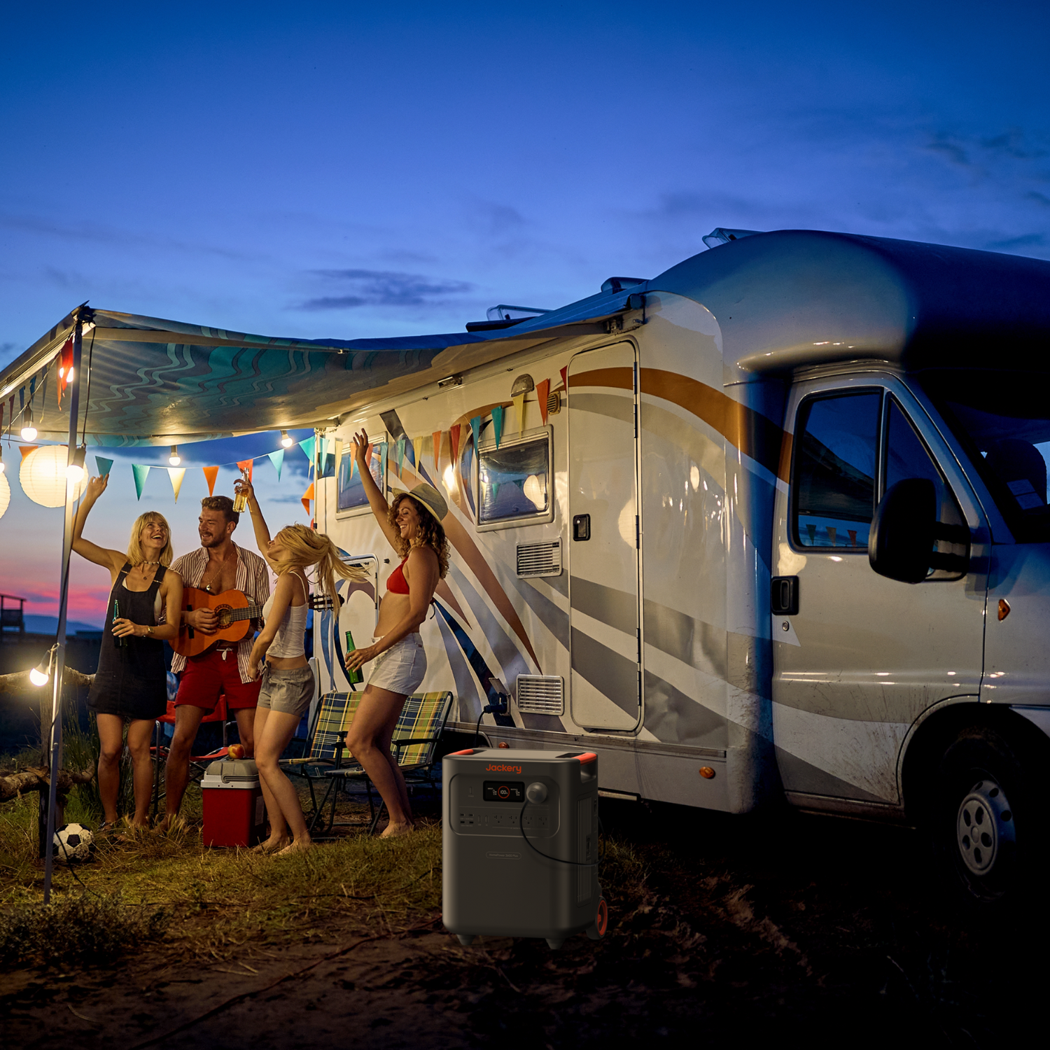 Group of people enjoying a campout near an RV with string lights and a Jackery HomePower 3600 Plus Portable Power Station