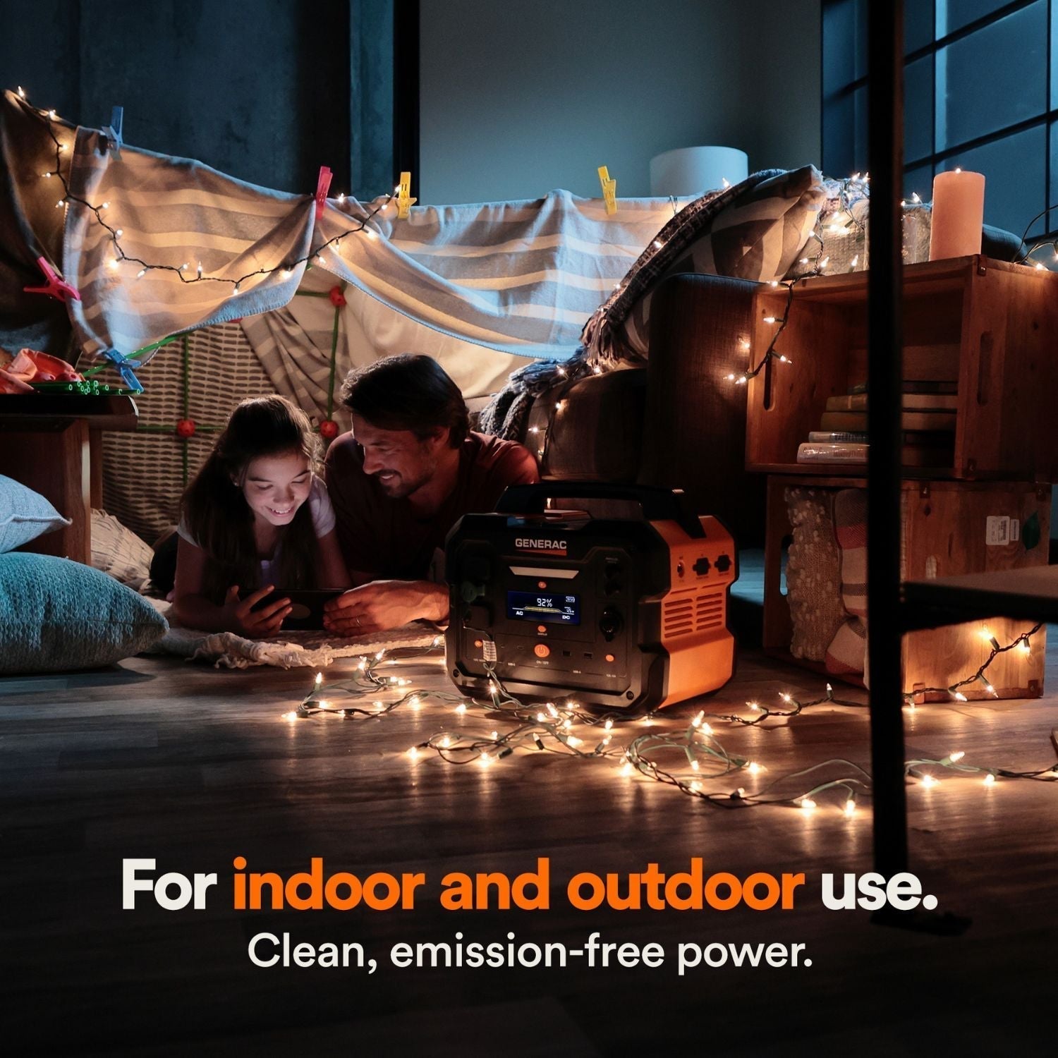 Person and child under a makeshift tent with string lights, using a Generac GB1000 Portable Power Station